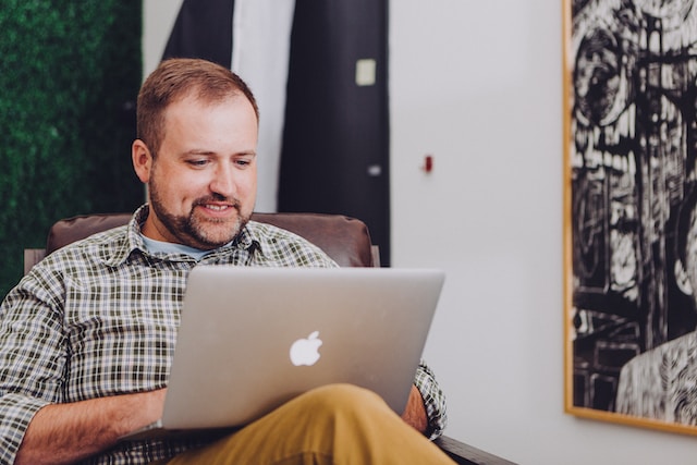 A guy happily looking at his laptop