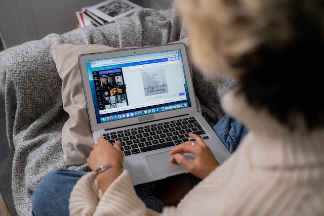 A woman working on her laptop, editing an image on Canva