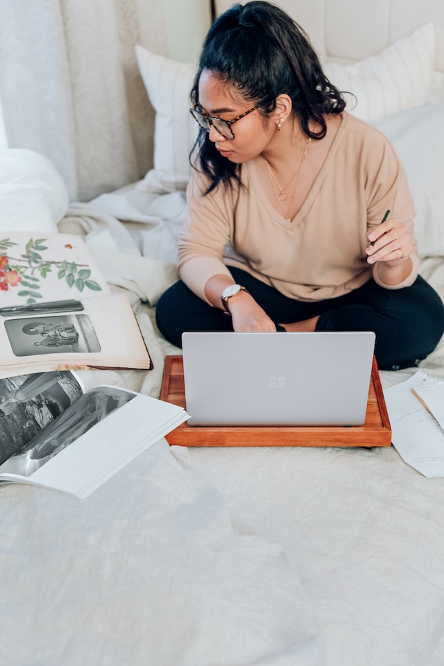 A woman working comfortably on her bed